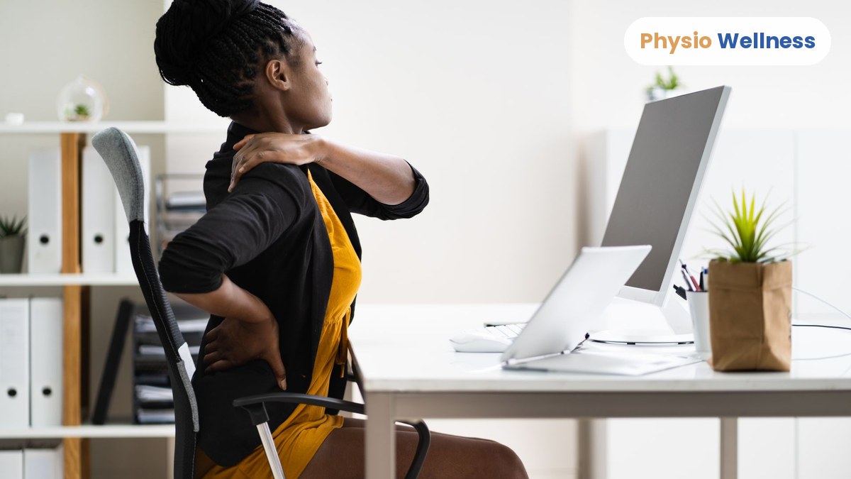 Desk worker holding her neck and lower back at her computer, a common pattern with a sedentary job