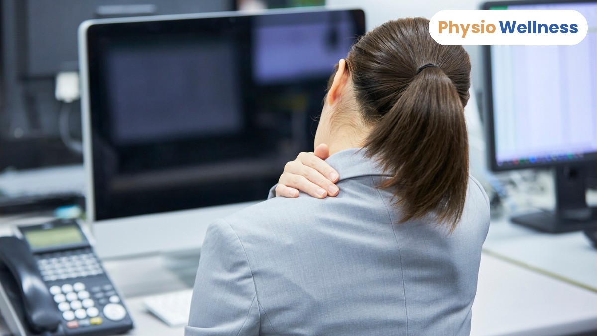 Office worker holding her aching shoulder while working at a desk