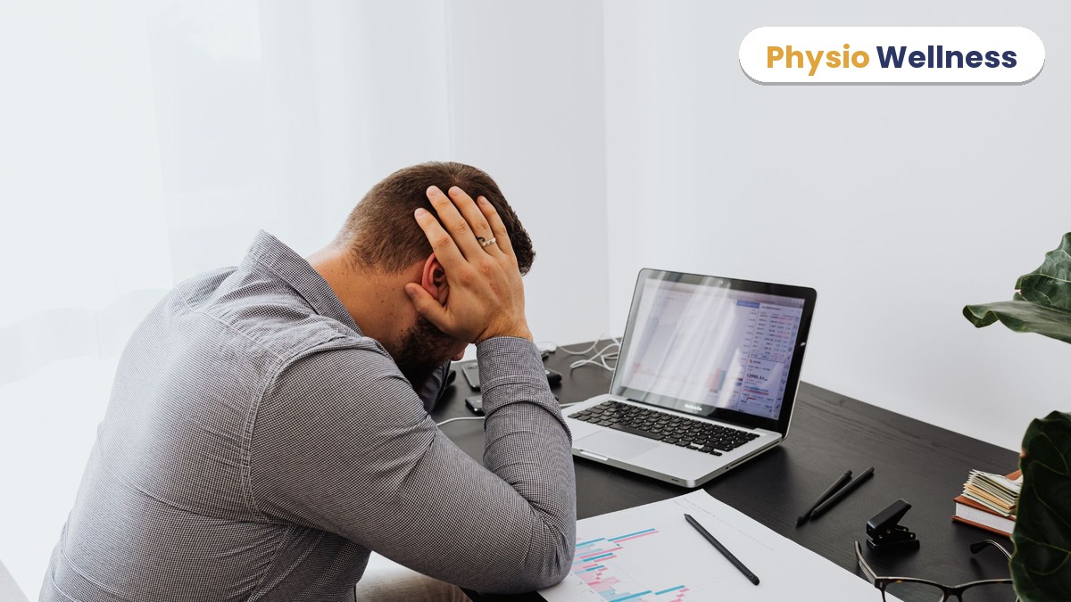Man at a desk with his head in his hands from a headache brought on by long screen work