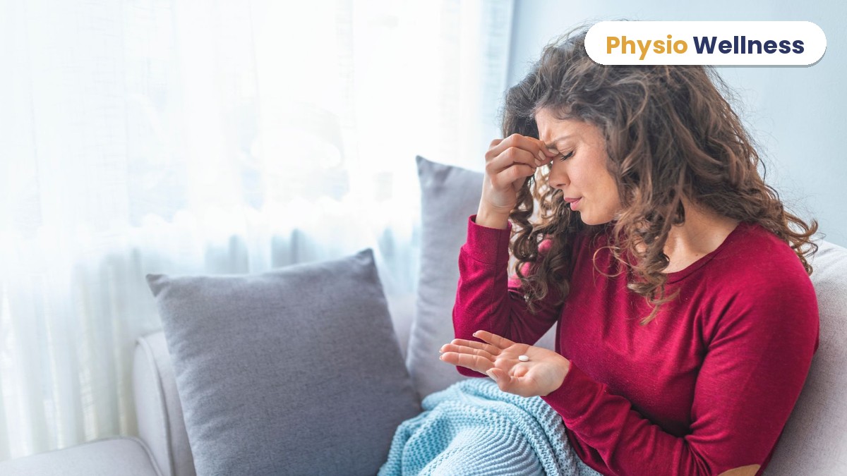 Woman on a couch with a headache holding a pain tablet