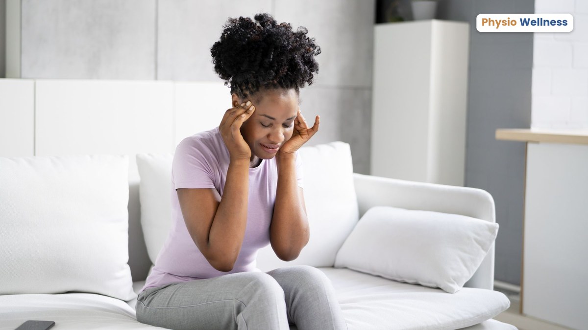 Woman sitting at home feeling dizzy and holding her head